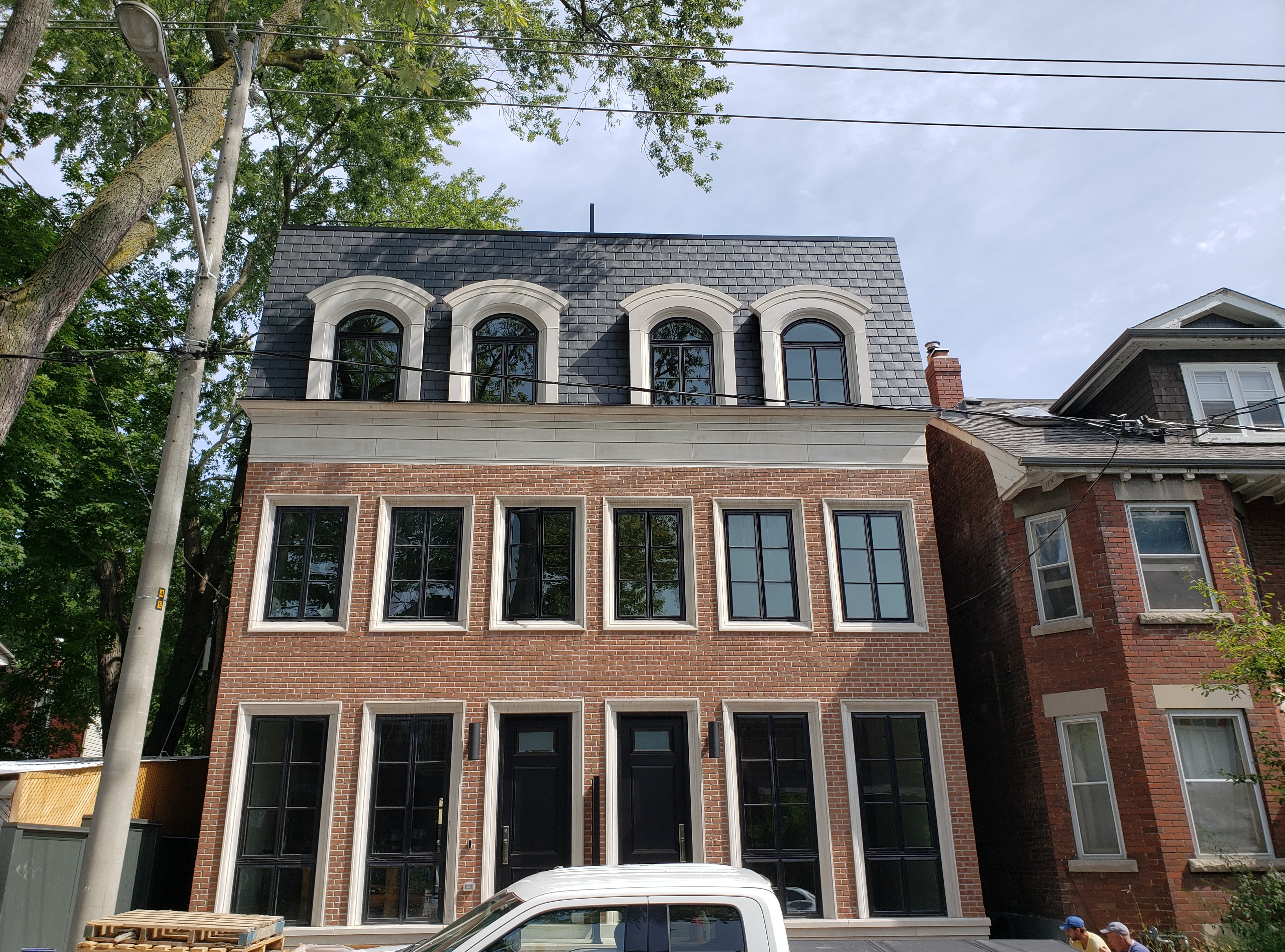 Brick multi-unit building with mansard roof and arched dormers