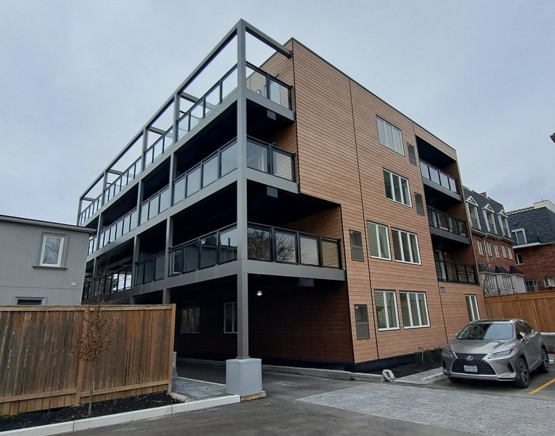 Modern multi-unit building with wood siding and glass balconies